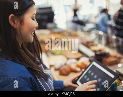 Cassa sorridente utilizzando il registratore di cassa touch screen nel bar Foto Stock