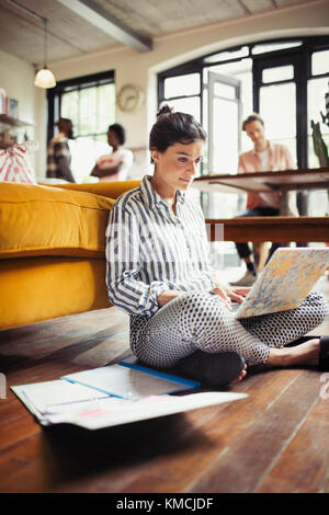 Freelance femminile che lavora su un computer portatile sul pavimento del soggiorno Foto Stock