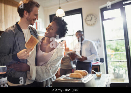 Affettuosa coppia abbracciare e mangiare pane tostato in cucina mattina Foto Stock