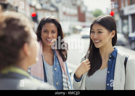 Sorridenti amici donne che parlano su strada urbana Foto Stock