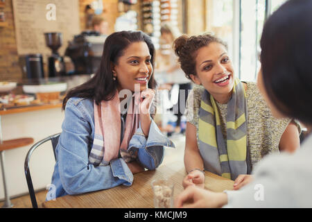 Sorridenti amici donne che parlano al tavolo del caffè Foto Stock