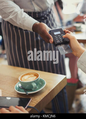 Il cliente paga il cameriere con lettore di carte di credito al tavolo del caffè Foto Stock