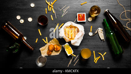 Sfondo di birra fresca birra e spuntini per lui su una grande tavola nera. La birra party. vista superiore Foto Stock