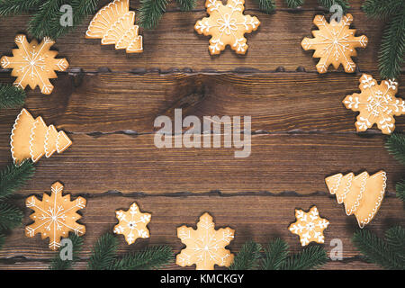 Il Natale di panpepato, Abete rami in forma di un telaio in legno marrone dello sfondo. Composizione di natale. Appartamento laico, vista dall'alto, spazio libero Foto Stock