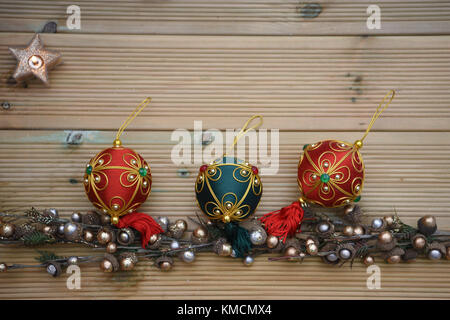 Fotografia di natale con legno rustico sfondo e copiare lo spazio e addobbi per l'albero di rosso verde baubles con una candela accesa e acorn filiali Foto Stock