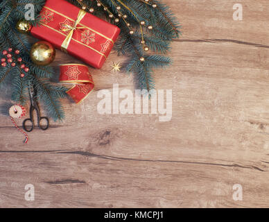 Sfondo di natale con albero di Natale decorato ramoscelli e dono avvolto su legno. Vista da sopra con copia spazio. Tonica immagine. Foto Stock