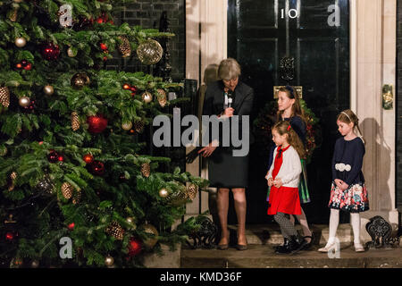 Londra, Regno Unito. 6 dicembre, 2017. ministro Theresa Maggio si prepara alla luce di Downing street albero di natale con giglio bo morgan, 5, sophie vysata, 8, e emily legno, 7. La struttura è stata donata dal Galles a base di freschi di gower alberi di Natale, che ha vinto l'albero di Natale un coltivatore del coltivatore di associazione del premio di anno è arredata con baubles e luci e sormontata da una stella ed è la prima volta che un albero di Natale dal Galles sorge al di fuori 10 di Downing street. Foto Stock