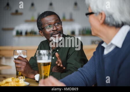 Senior amici di parlare e di bere birra Foto Stock