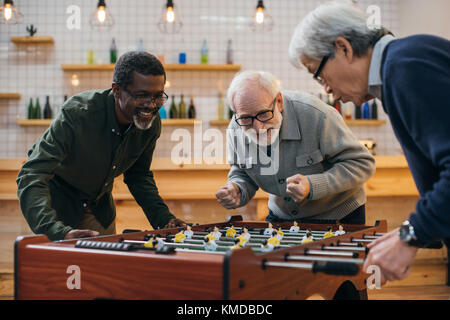 Senior amici a giocare il calcio balilla Foto Stock