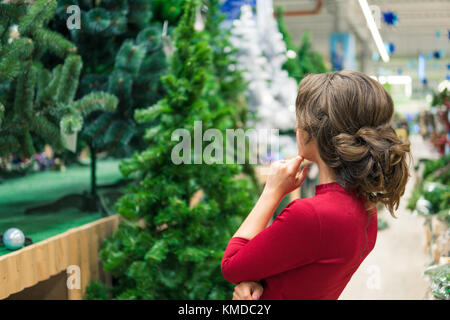 Cliente soddisfatto ragazza scegliendo Albero di natale per il nuovo anno Foto Stock