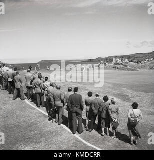 1951, vista storica del Royal Portrush Golf Club sulla costa di Antrim, Irlanda del Nord, che in quest'anno è stato il luogo del torneo di golf Briitsh Open e vediamo spettatori ben vestiti che si trovano intorno a un verde costiero per guardare il putt dei golfisti. Il famoso torneo di golf, ora conosciuto come semplicemente "The Open", vide questa edizione sulla costa rocciosa dell'Atlantico dell'Irlanda del Nord vinta dal golfista inglese Max Faulkner, la sua unica grande vittoria. Foto Stock