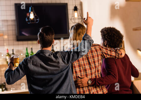 Gli amici a guardare la tv in bar Foto Stock