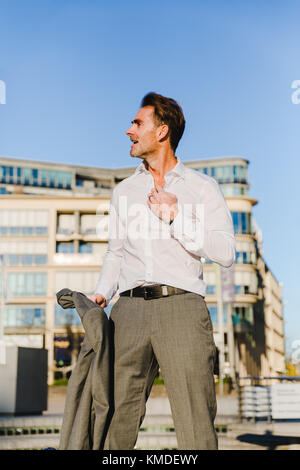 Immagine di un imprenditore nella città che tira della sua giacca Foto Stock