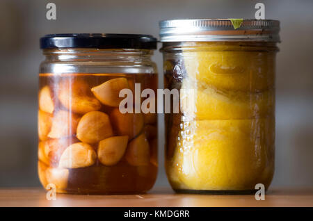 Aglio sott'aceto di miele e decapati limoni sono mostrati in vasetti di vetro Foto Stock