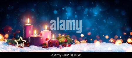 Quattro candele rosse dell'avvento con quattro candele accese e decorazione  di natale che giace nella neve come modello Foto stock - Alamy