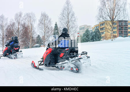 Persone a cavallo delle motoslitte sul lago ghiacciato in inverno rovaniemi, Lapponia, Finlandia Foto Stock