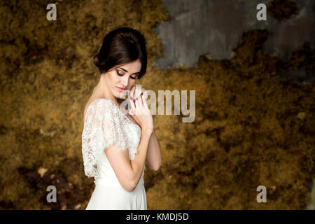 Sposa nel bel vestito seduti su una sedia per interni in dark studio interno come a casa. Foto Stock