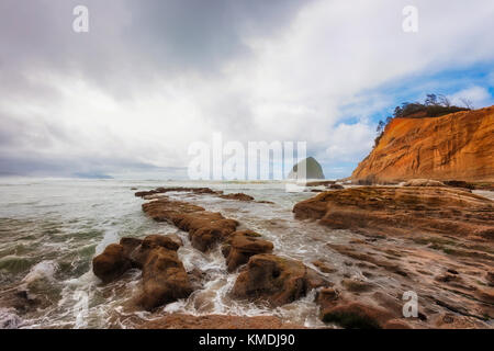 Sotto drammatico cielo nuvoloso la vista dalle sponde rocciose di cape kiwanda nella città del pacifico, sulla costa dell'Oregon Foto Stock