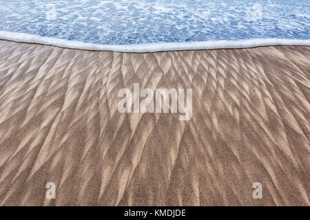 Abstract closeup immagine del pattern di sabbia a sinistra da un onda in ritirata sulla spiaggia di città del pacifico sulla costa dell'Oregon Foto Stock