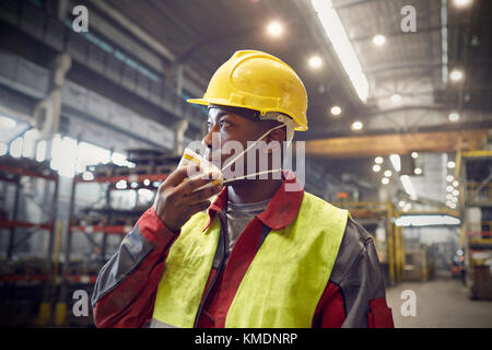 Steelworker rimozione maschera protettiva in acciaieria Foto Stock