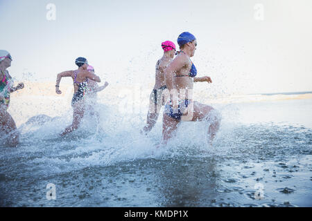 Femmina acqua aperta nuotatori in esecuzione e spruzzi in ocean surf Foto Stock