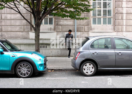 Giovane uomo in King Cross per controllare il suo telefono cellulare Foto Stock