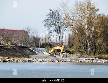 Slavyansk-su-kuban, Russia - 8 novembre 2016: rafforzare gli argini del fiume nella città. riempimento di macerie e livellamento del trattore con Foto Stock