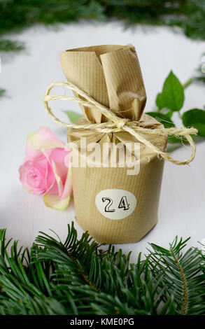 Dicembre 24th. Un dono mostra data 24 dicembre in legno bianco con sfondo verde rami di abete. La Vigilia di Natale. Foto Stock