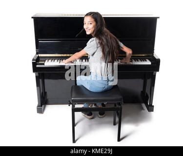 Teenage brunette girl e nero pianoforte verticale in studio Foto Stock