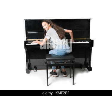 Teenage brunette girl e nero pianoforte verticale in studio Foto Stock