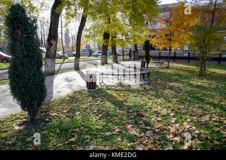 Slavyansk-su-kuban, Russia - 8 novembre 2016: banco in un parco d'autunno. pavimento di piastrelle e pattumiera. Foto Stock