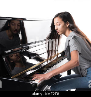 Teenage brunette girl e nero pianoforte verticale in studio Foto Stock