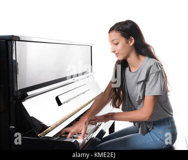Teenage brunette girl e nero pianoforte verticale in studio Foto Stock