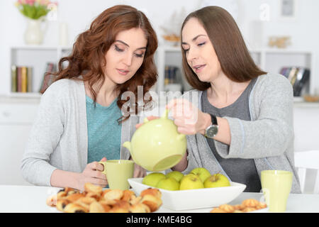 Due femmina sorridente amici seduti a tavola Foto Stock