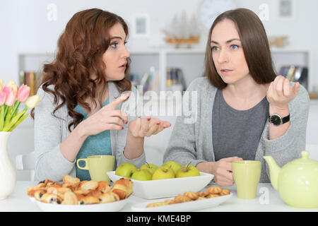 Due femmina sorridente amici seduti a tavola Foto Stock