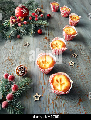 Spuntini di Natale: limone mini muffin in involucri a scacchi sul tavolo rustico con decorazioni di Natale in rosso e verde. Foto Stock