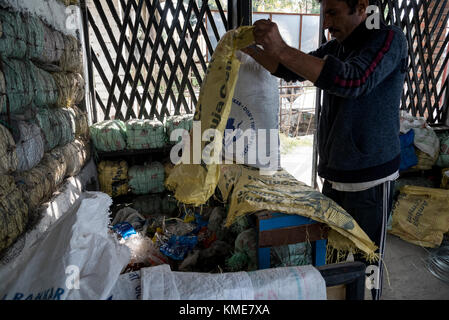 Un uomo la miscelazione fino involucri di plastica prima della loro trasformazione per fare mattoni di plastica per evitare effetti nocivi di materie plastiche, essa contribuisce alla sviluppo sostenibile Foto Stock