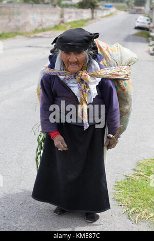 Coppia donna indigena in costume tradizionale che trasportano merci a piedi lungo una strada, northern Ecuador, Sud America Foto Stock