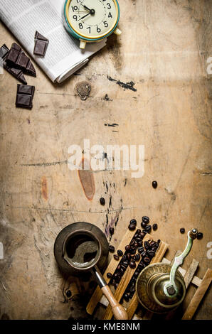 Caffè moka pot con sveglia e giornali. su sfondo di legno. Foto Stock