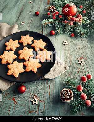 Rustico sfondo di Natale in verde e rosso a forma di stella i cookie su piastra nera con decorazioni di Natale. tonica immagine. Foto Stock