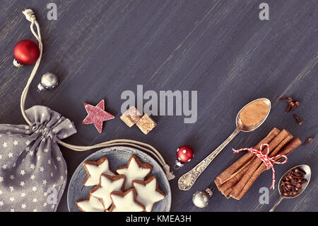 Natale sfondo in grigio, bianco e rosso su legno scuro. vista dall'alto su biscotti di Natale, spezie e decorazioni. tonica immagine, lo spazio di testo Foto Stock