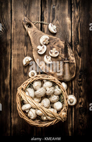 Funghi di taglio con un coltello su un vecchio albero tronco. su sfondo di legno. Foto Stock