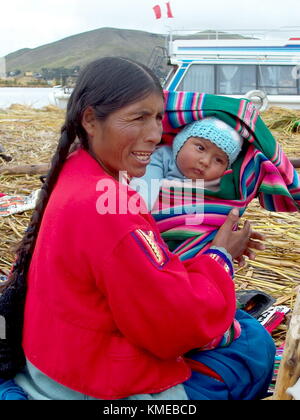 Puno, Perù, 3 gennaio 2007: uros donna detiene il bambino su un isola galleggiante, il lago Titicaca, Perù Foto Stock