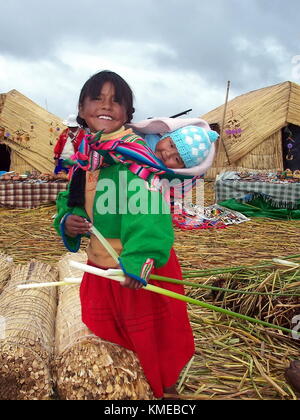 Puno, Perù, 3 gennaio 2007: bambina con un bambino su un uros isola galleggiante, il lago Titicaca, Perù Foto Stock