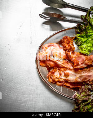 Pancetta fritta con verdi. sul tavolo in metallo. Foto Stock