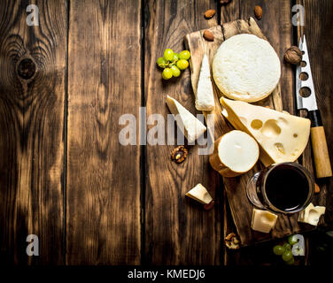 Vino rosso con grossi pezzi di formaggio e dadi. su di un tavolo di legno. Foto Stock