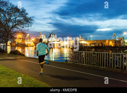 Un runner lungo il lungomare di notte a Seattle, WA. Foto Stock
