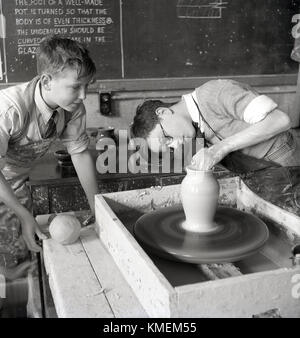 Degli anni Cinquanta, storica Scuola classe ceramica, due ragazzi in un'Aula rendendo pentole di creta a mano usando una ruota di ceramiche, Inghilterra, Regno Unito. Foto Stock