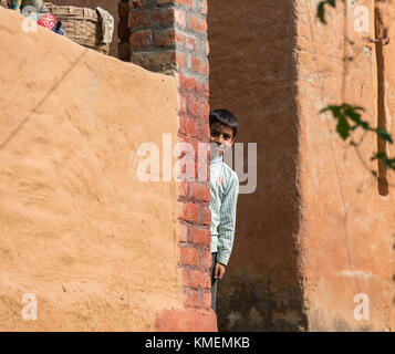 Un giovane ragazzo indiano guardando da dietro la parete. Foto Stock