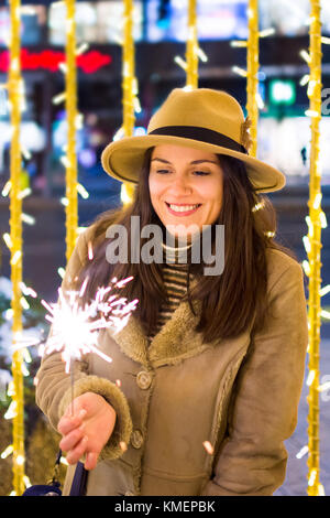 Ragazza con il fuoco brilla con festosa sfondo illuminato Foto Stock